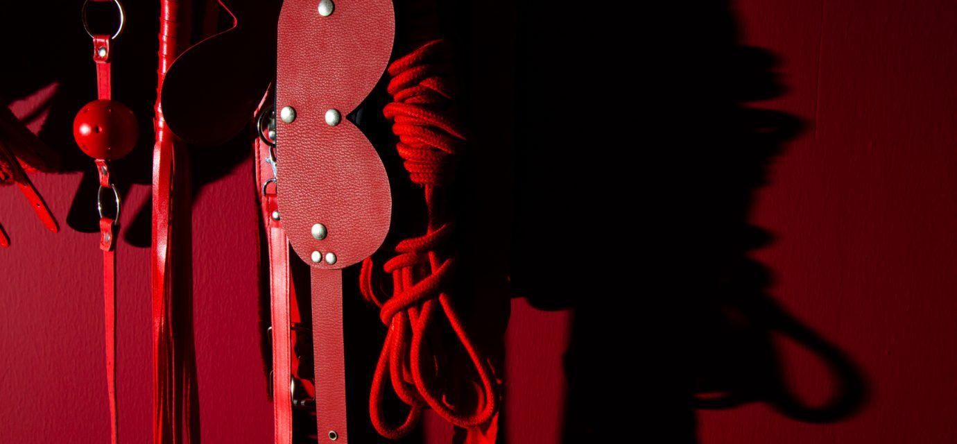 Swingers Club - close-up-sex-toys-hanging-against-wall