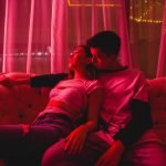 Swingers Club - view-couple-embracing-while-sitting-sofa-illuminated-room
